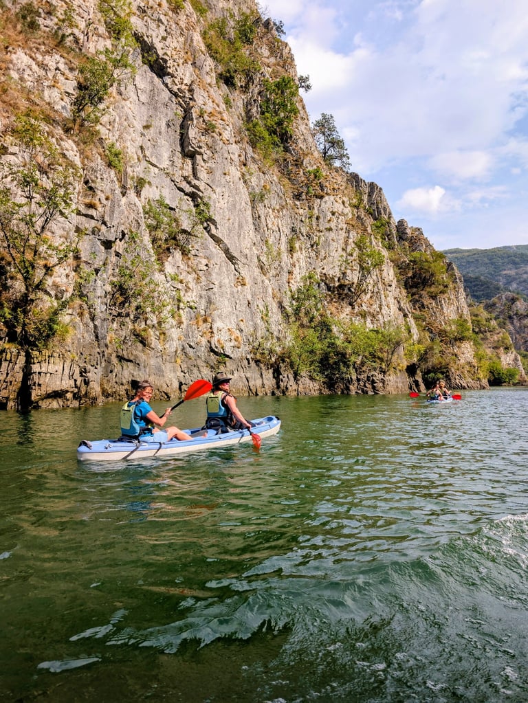 people kayaking in Matka Canyon with beautiful clif walls, North Macedonia 