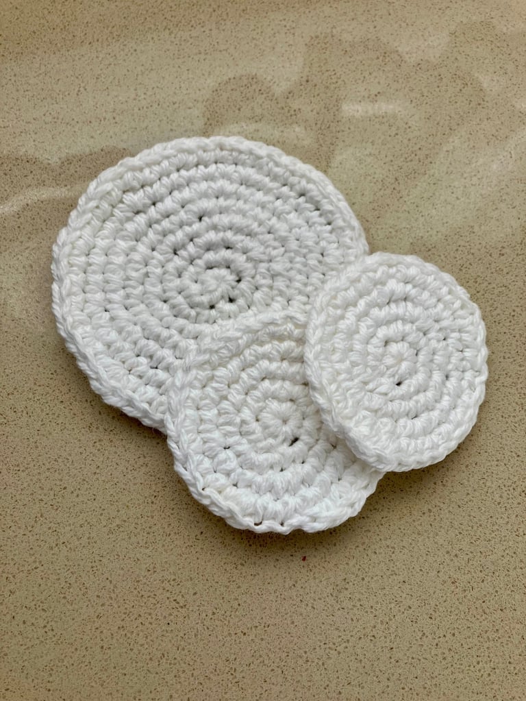 3 round white crocheted face scrubbies lying on each other