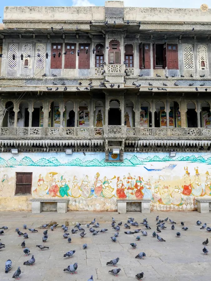Lakeside steps of Gangaur Ghat with pigeons flying and havelis behind, udaipur Rajasthan.