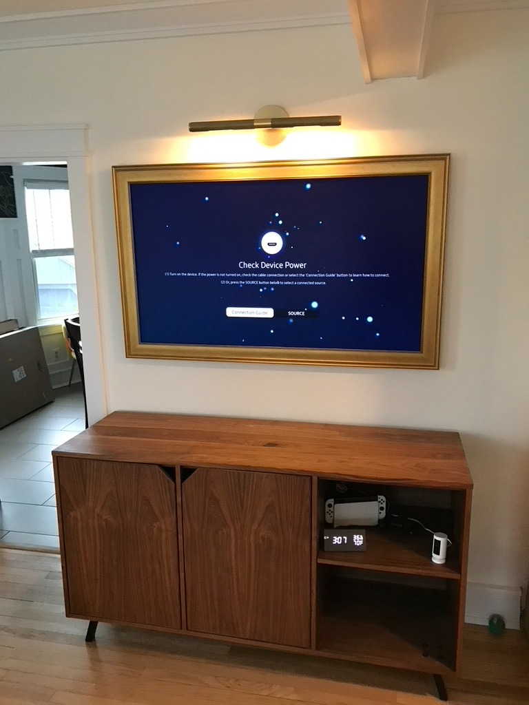samsung the frame TV mounted on the wall with art light overhead in living room