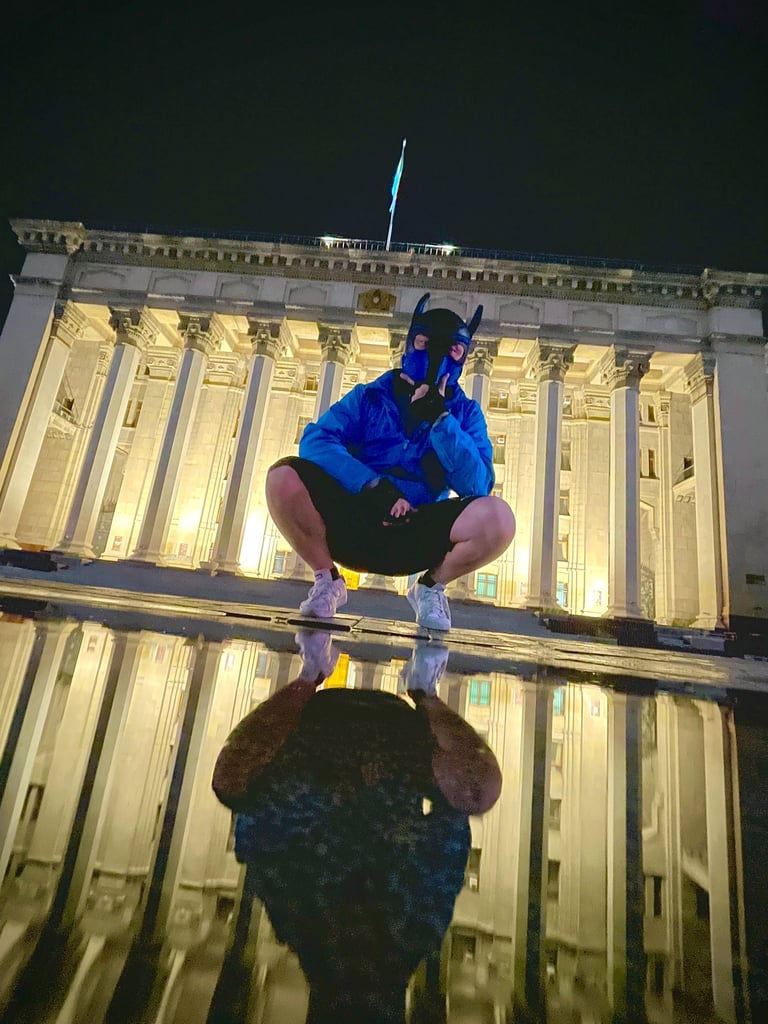 Man in pup mask posing near monument at night.