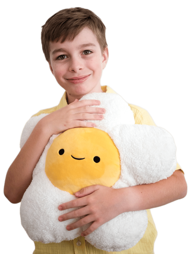 A smiling young boy holding a daisy-shaped plush
