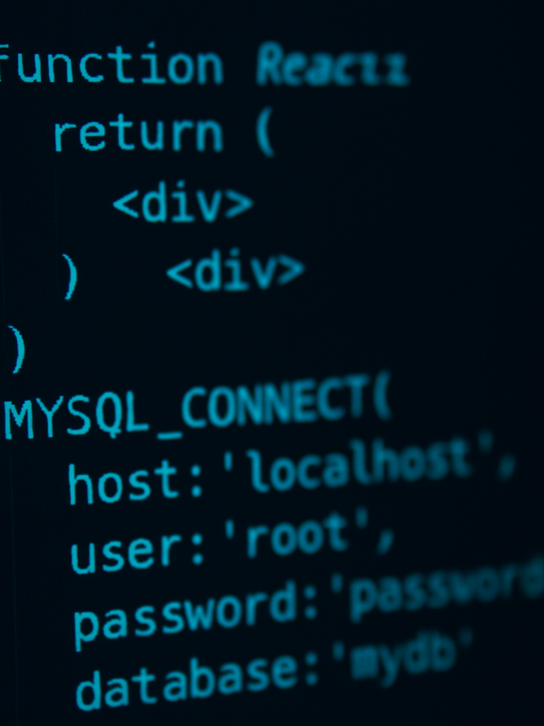 Macro close-up of clean, high-contrast React code on a dark-mode IDE screen, cool cyan terminal glows reflecting off dark glass, sharp focus on database connection strings, low-key dramatic lighting.