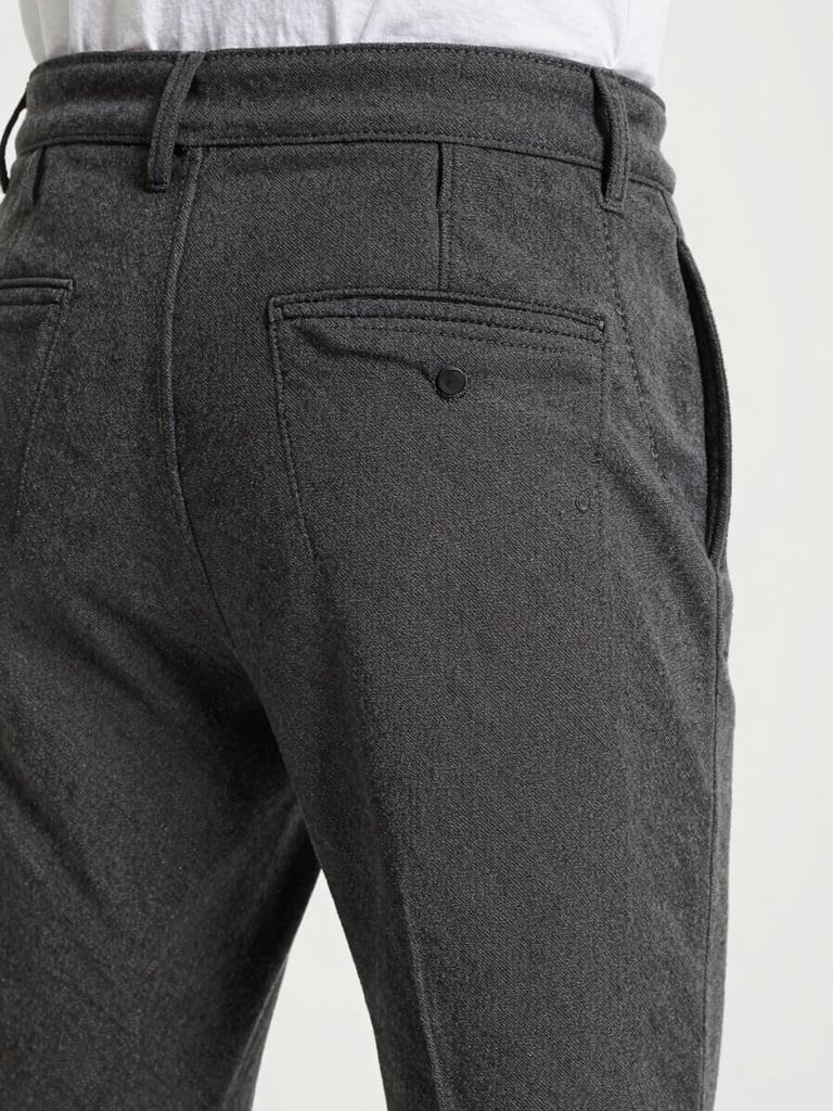 Portrait orientation showing a close-up of charcoal cotton canvas trousers with clean flat-felled seams and technical pocket details.