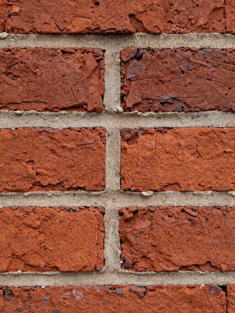 Macro close-up of weathered historic red brick with freshly struck, perfectly matched lime mortar joints, overcast natural light emphasizing texture