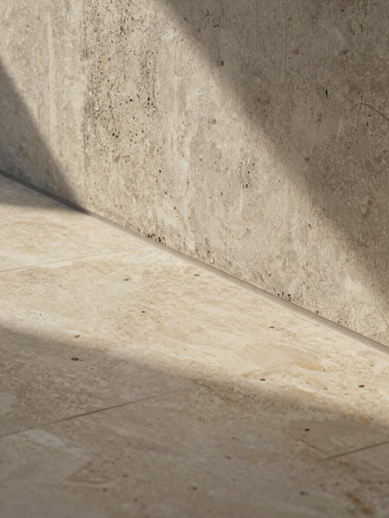 Macro architectural photograph of a flawless transition between a polished travertine floor and a textured raw concrete wall, soft golden light