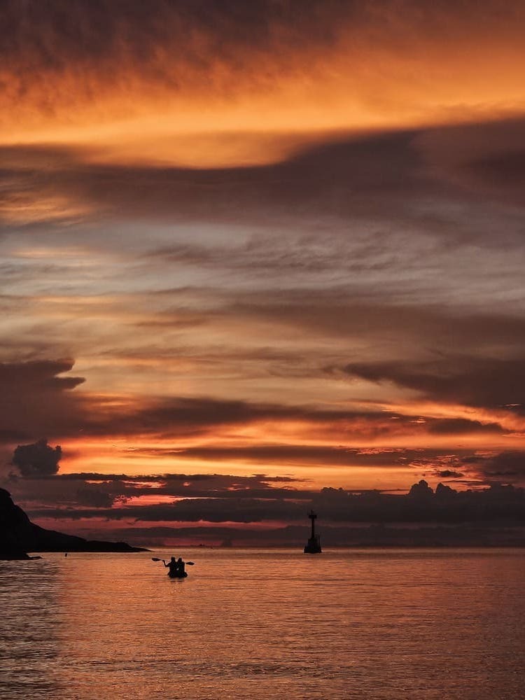sunset in the ocean and people kayaking