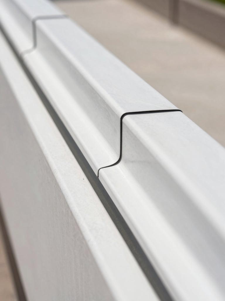 Macro close-up of a clean water barrier installation behind EIFS drainage tracks, showing technical precision and sealed joints under bright natural daylight