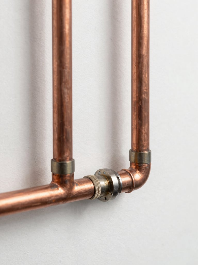 A clean, newly installed copper pipe system on a white wall, showing precise solder joints, bright daylight, sharp macro focus, technical engineering style.