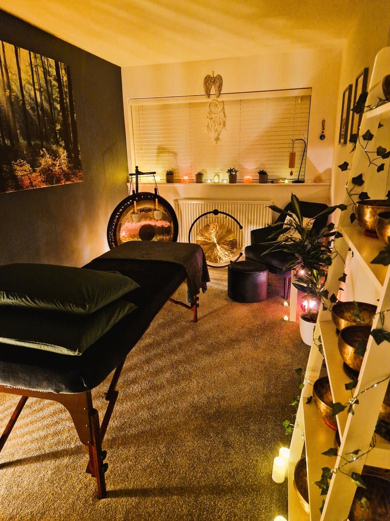 Studio with treatment couch, chair, gongs and shelf with Himalayan singing bowls
