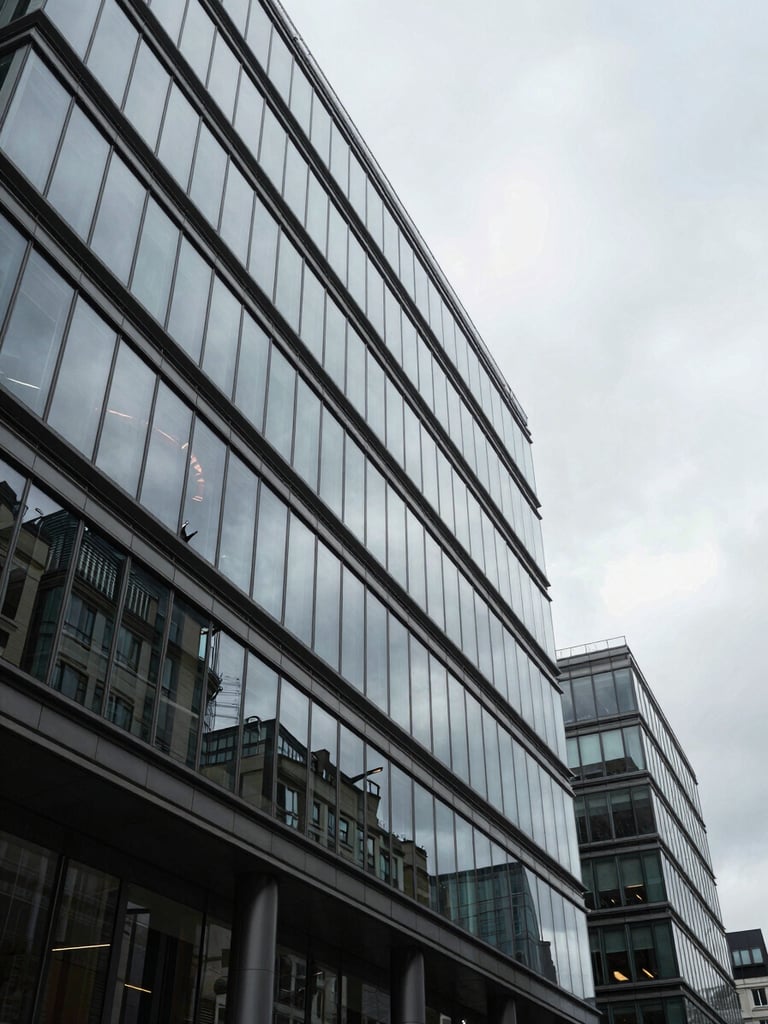 Architectural low angle shot of a modern corporate glass office building reflecting overcast London sky, crisp natural daylight, cool desaturated tones, sharp focus.