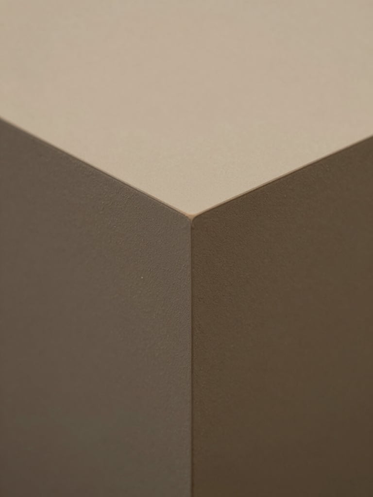 Close-up straight-on detail of a finished work piece — precise edges and controlled studio lighting, muted warm-toned surface, no competing background elements, full-frame crop