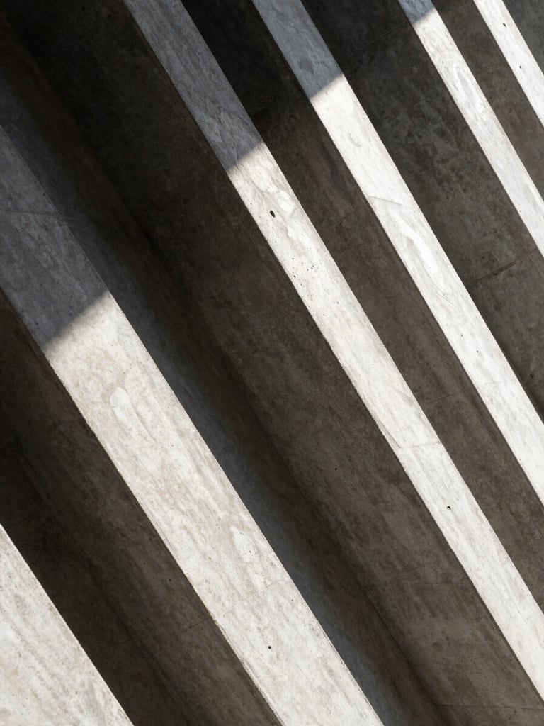 Abstract architectural concrete lines with sharp diagonal shadows under natural daylight, conveying structure and clarity.