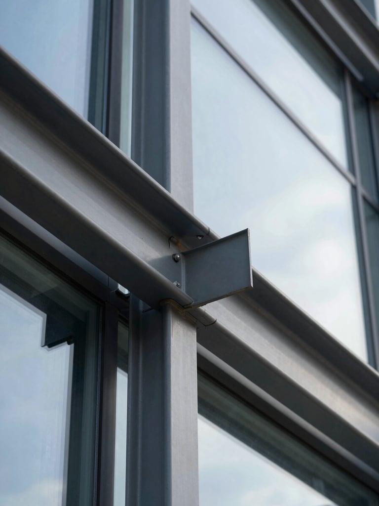 Tight macro shot of structural steel and modern glass panels on a commercial building facade, bathed in bright, crisp daylight.