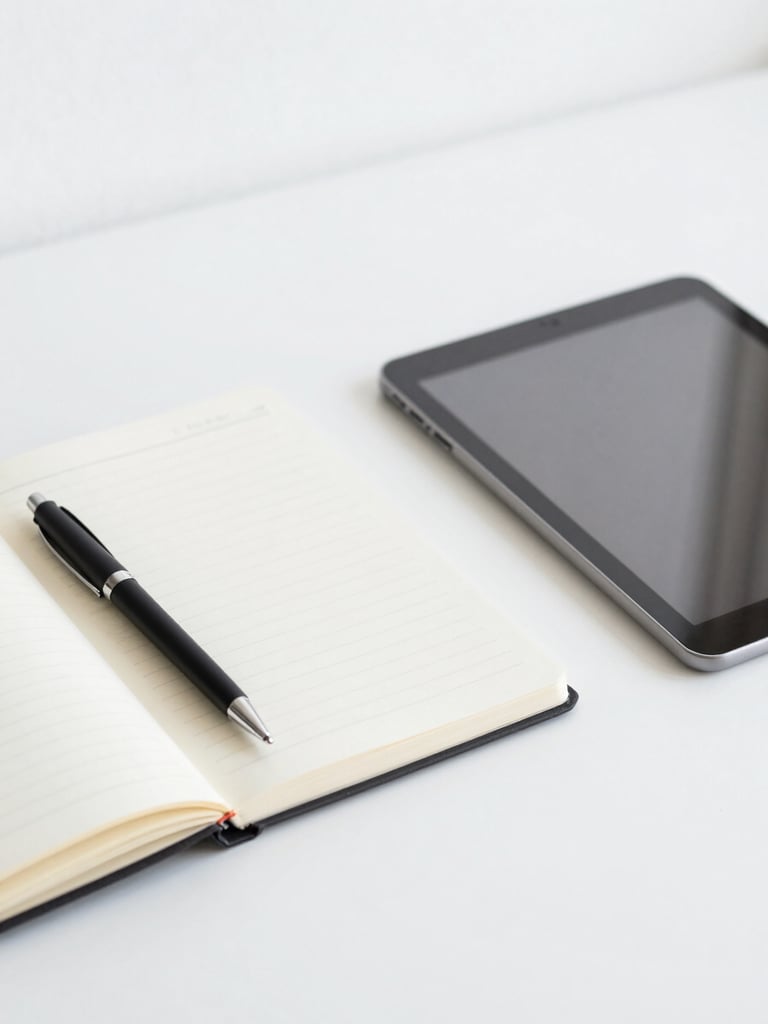 Minimalist close-up of an organized remote workspace desk with a notebook, pen, and clean tablet under bright neutral daylight.