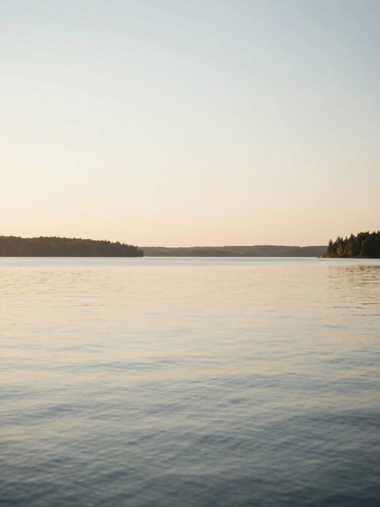Serene natural landscape of a calm Canadian lake at golden hour, soft horizon, diffused warm light, elegant and quiet atmosphere, 35mm