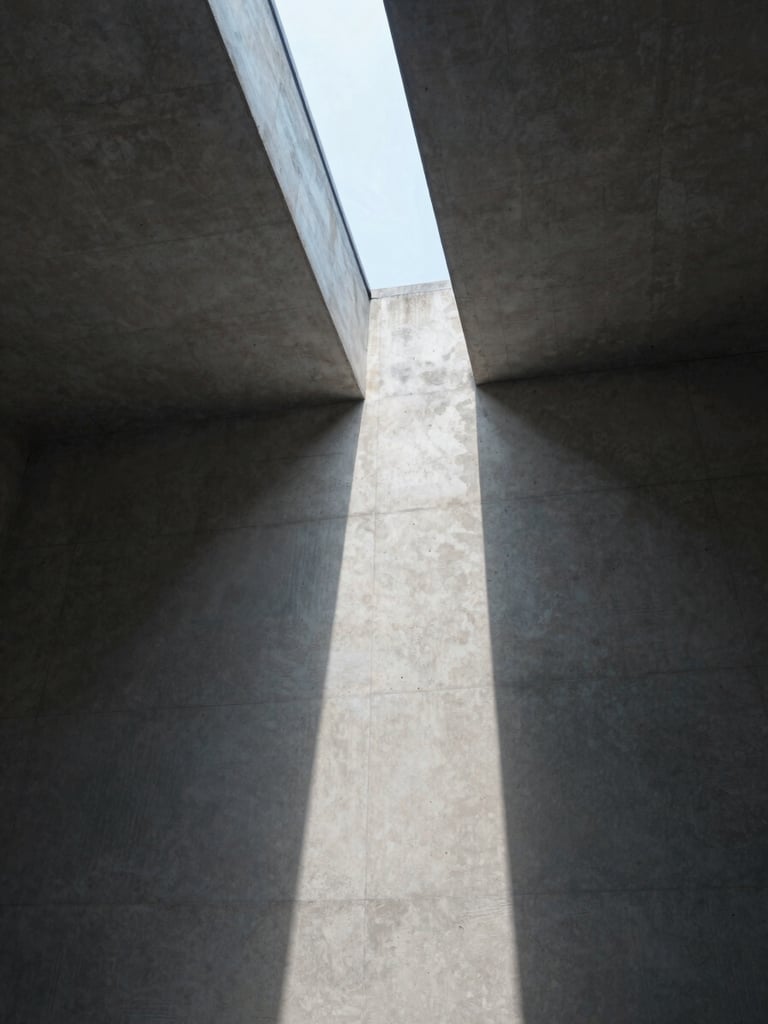 Wide architectural interior shot looking upward at a concrete ceiling where raking natural light enters through a narrow clerestory slot, casting a single sharp line of diffused daylight across the raw surface — no people, no furniture, just the geometry of light and shadow on the structure, photographed in cool north-facing daylight with soft gradation from deep shadow to pale gray stone