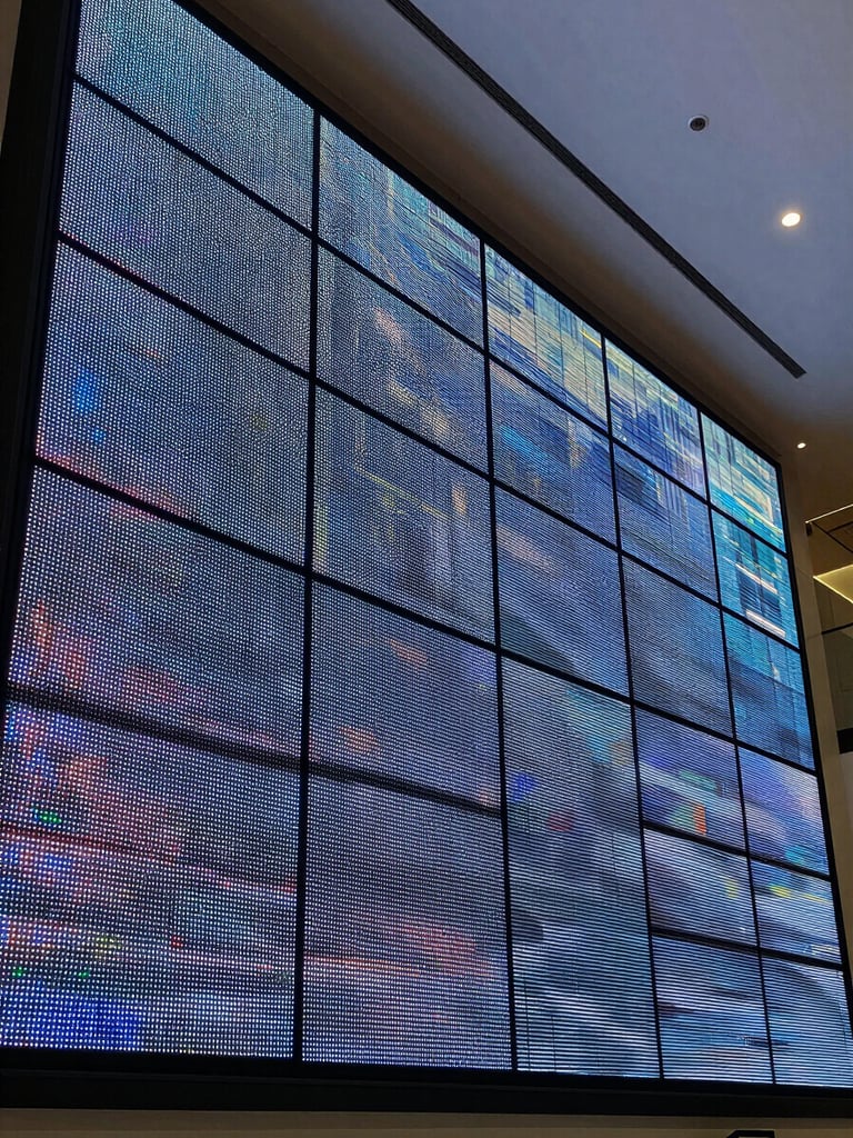 Close overhead architectural shot of a large-format LED videowall installed in a corporate lobby — panels perfectly aligned, cool studio lighting from above, individual pixel modules visible at the seams, no people, operational and powered on displaying abstract data
