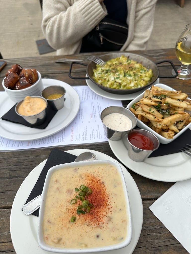 A table with pretzel bites, mac & cheese, french fries, and clam chowder