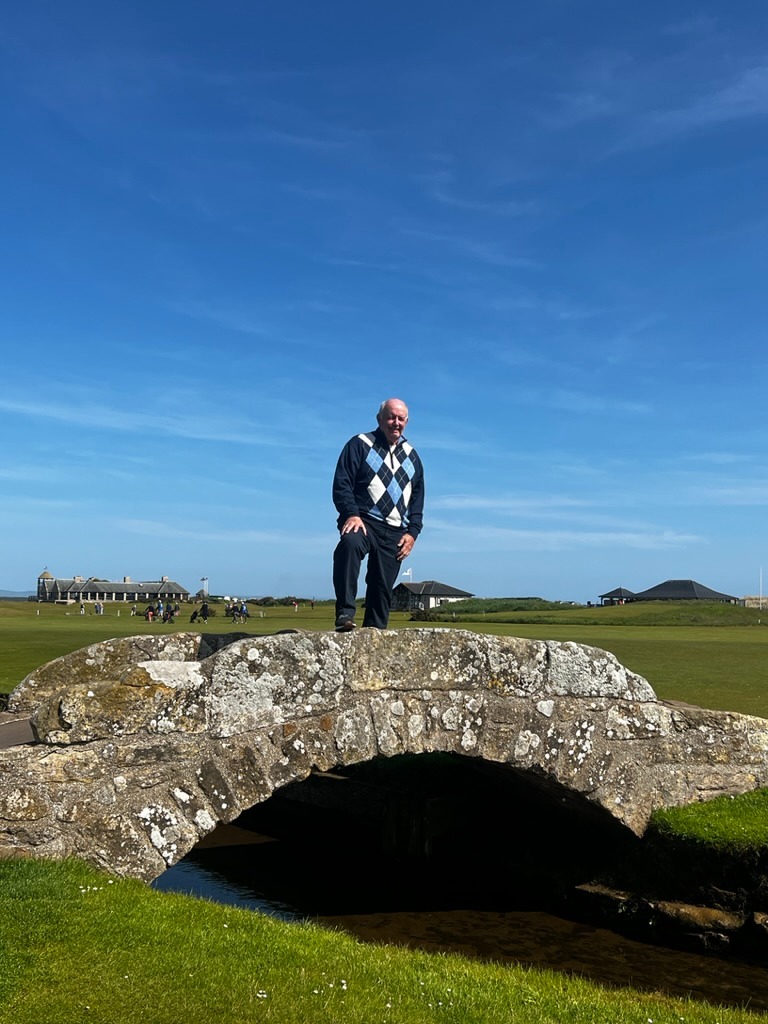 a man standing on a stone bridge over a stream