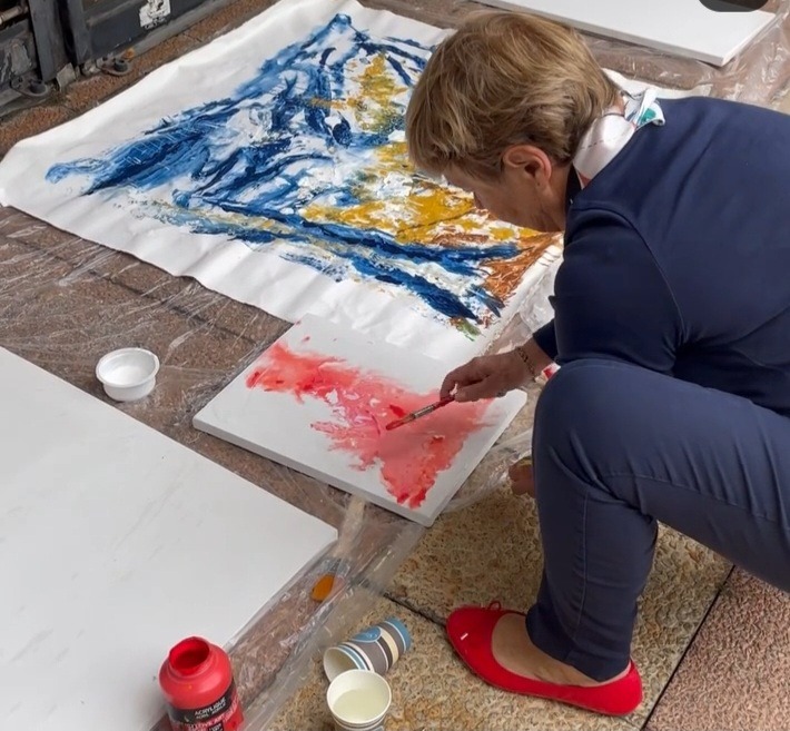 a woman is painting with a paintbrush