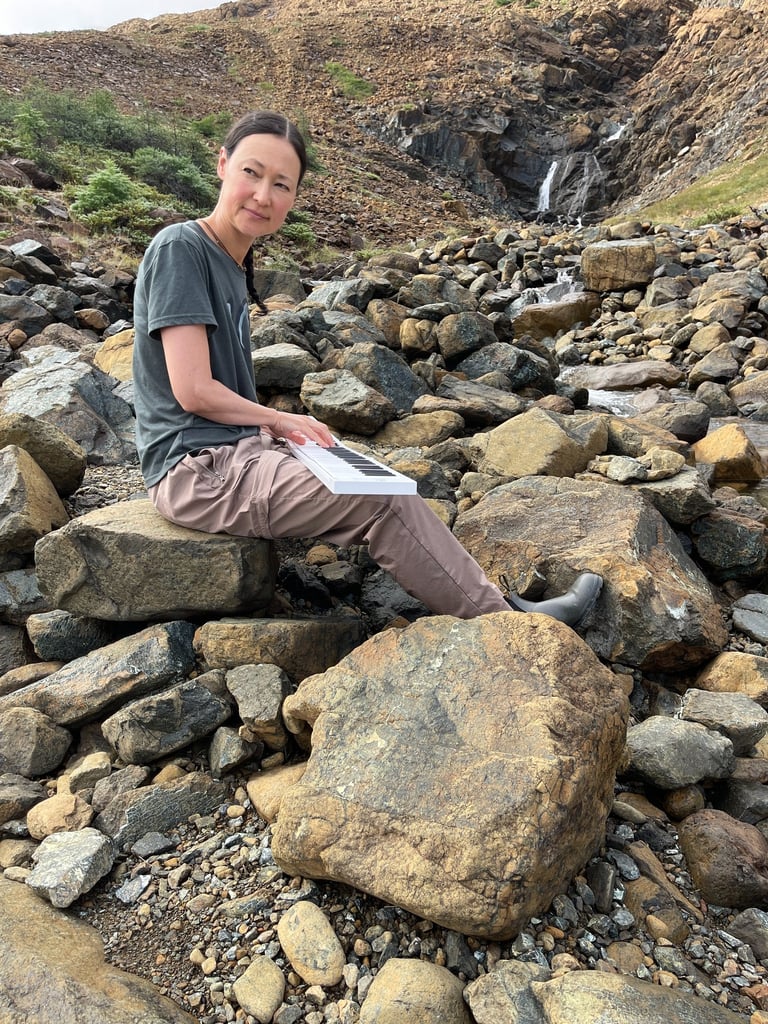 Composer Jen Smith Lanthier playing the keyboard outdoors in a natural setting