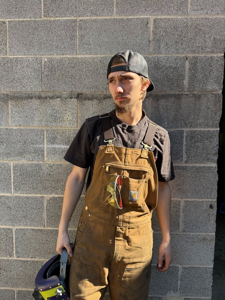 jaspar schirmer standing by a wall in his welding gear