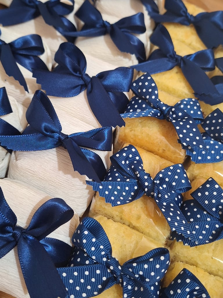 Wrapped party favors and gourmet cakes decorated with elegant navy blue satin and polka dot bows.