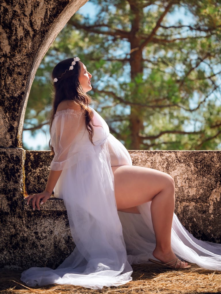 a woman in a white dress sitting on a stone wall