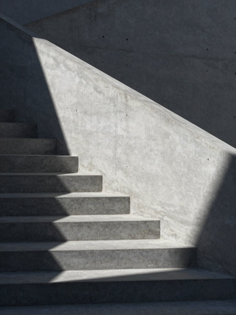 Stark minimalist architectural detail of concrete stairs and sharp geometric shadows under cool daylight, 50mm lens