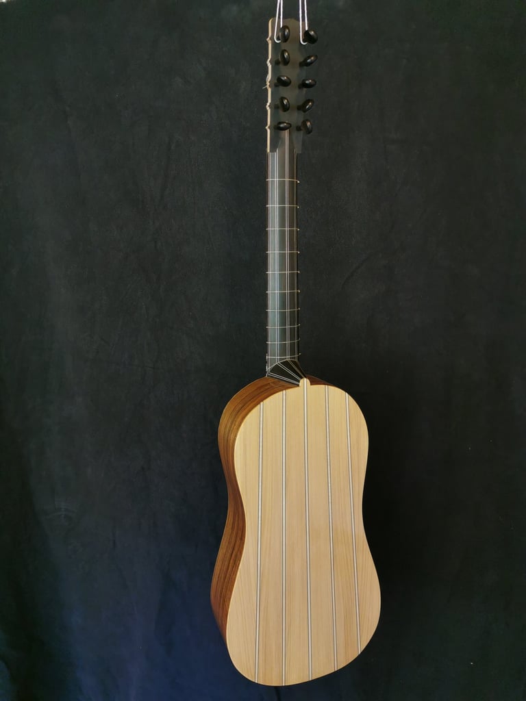 Handcrafted Baroque guitar with striped wooden back and long fretboard against a dark background.