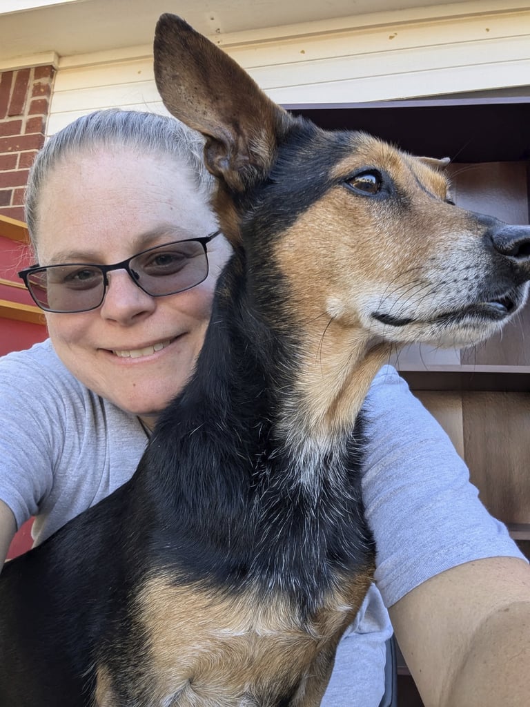 Laura Hooton on the left, in a grey tshirt, smiling, with a brown and black dog on the right.