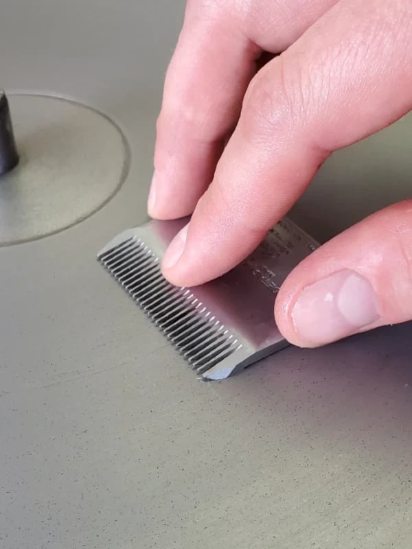 Professional clipper blade being sharpened with diamond sharpening equipment