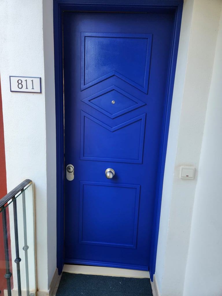 Modern vibrant blue apartment front door with geometric panels and house number 811.