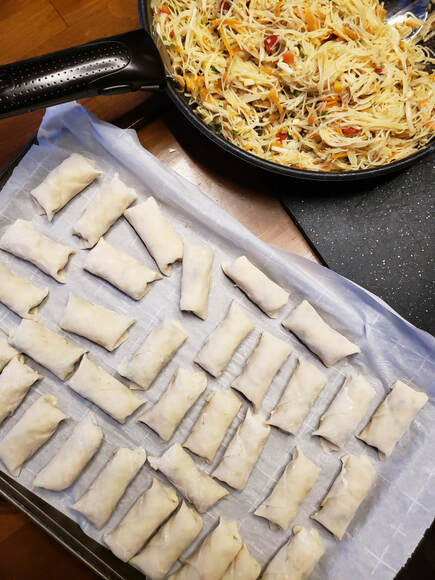 uncooked Thai spring rolls ready for freezing on parchment paper on a cookie sheet