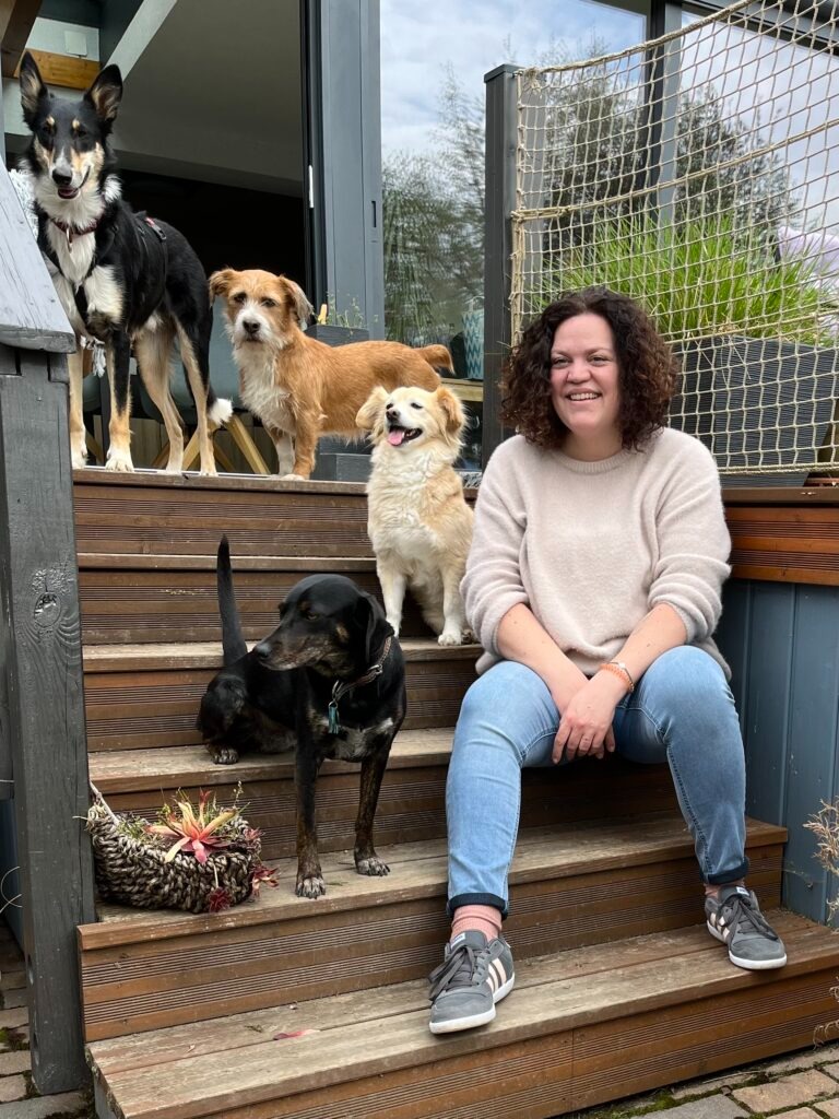 Julia sitzt mit 4 Hunden auf einer Treppe