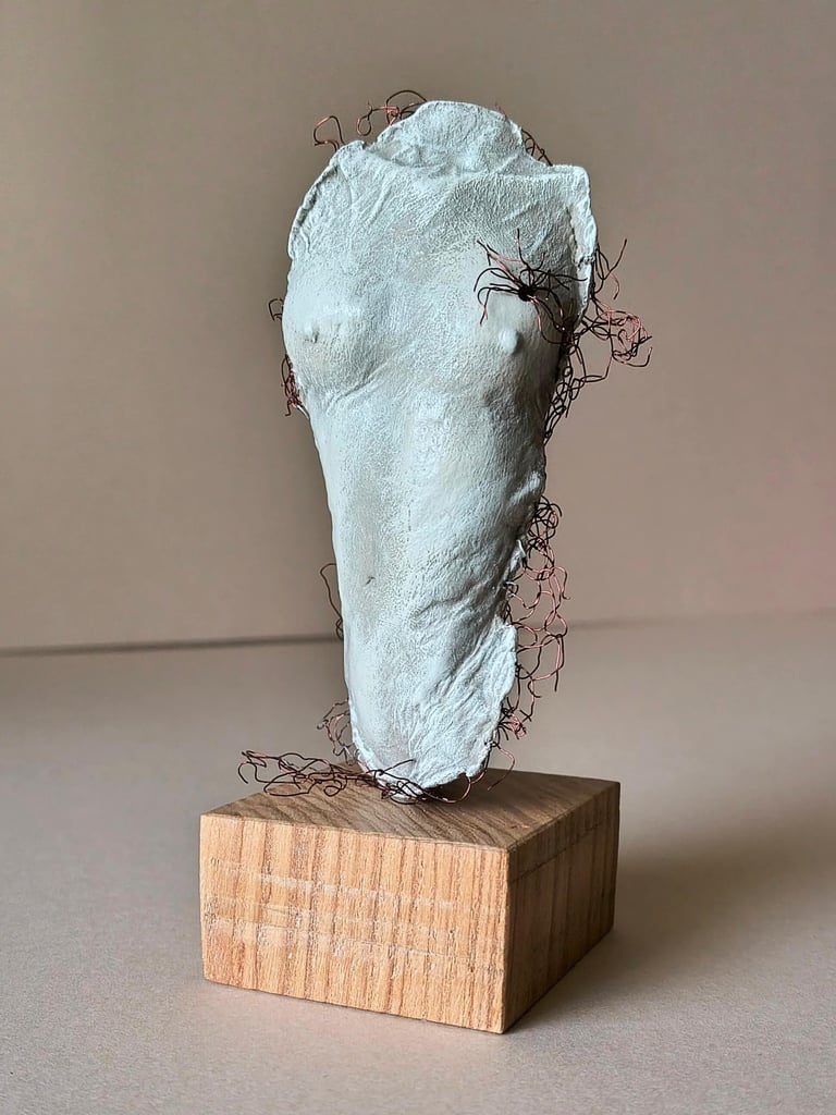 A plinth mounted sculpture of a female torso with wire around it and protruding through it.