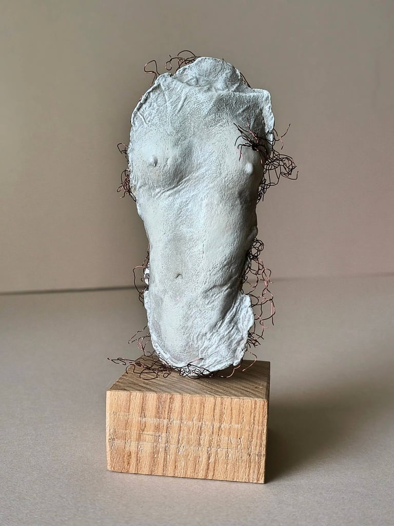 A plinth mounted sculpture of a female torso with wire around it and protruding through it.