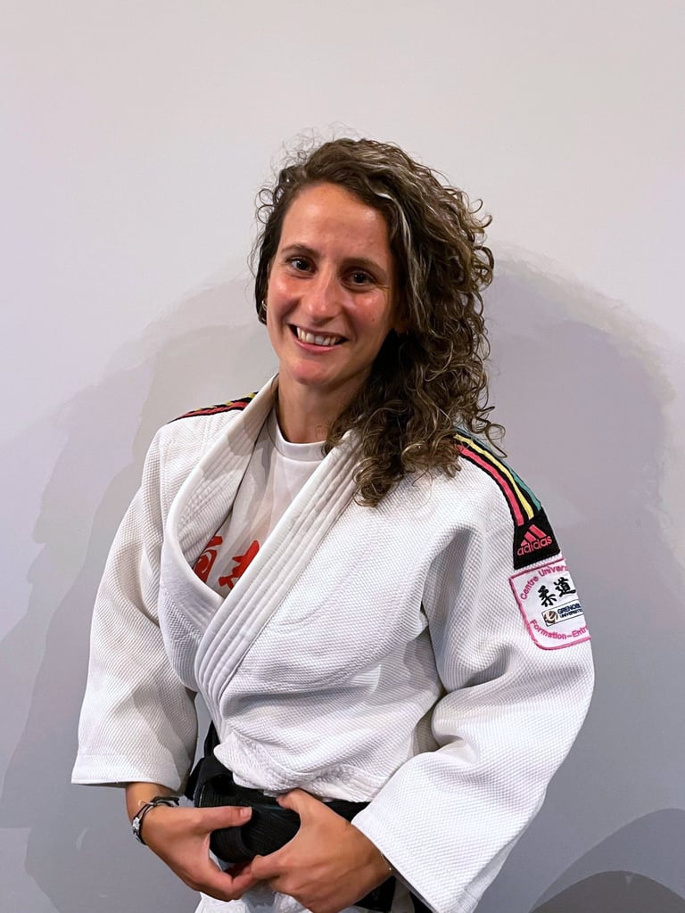 Une femme en kimono de Judo, portant une ceinture noire.