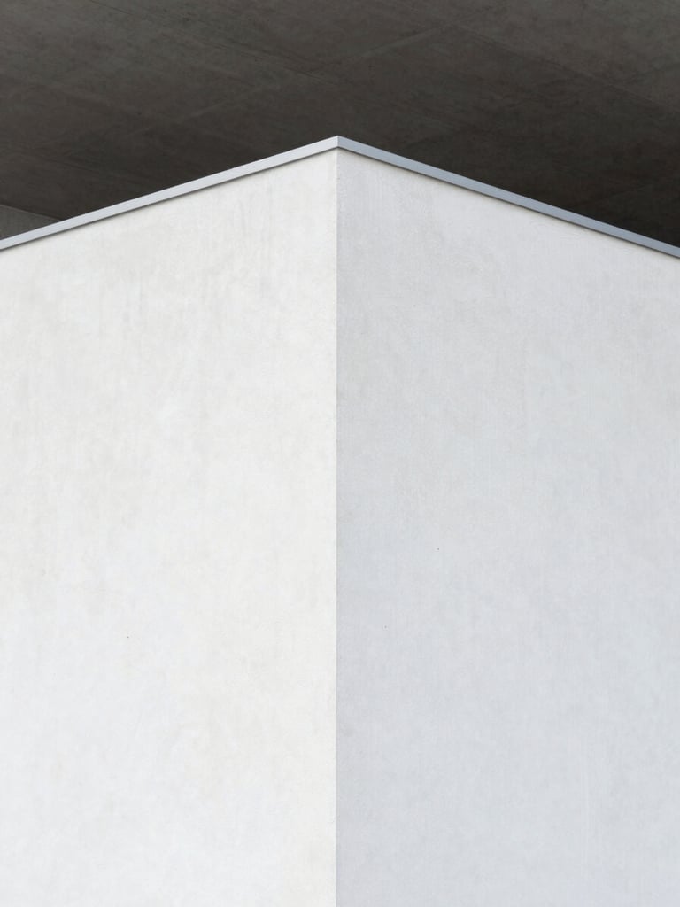 Sharp architectural angle of a pristine white plaster wall meeting a dark grey concrete ceiling, bright overcast Belgian daylight, clean minimalist texture.