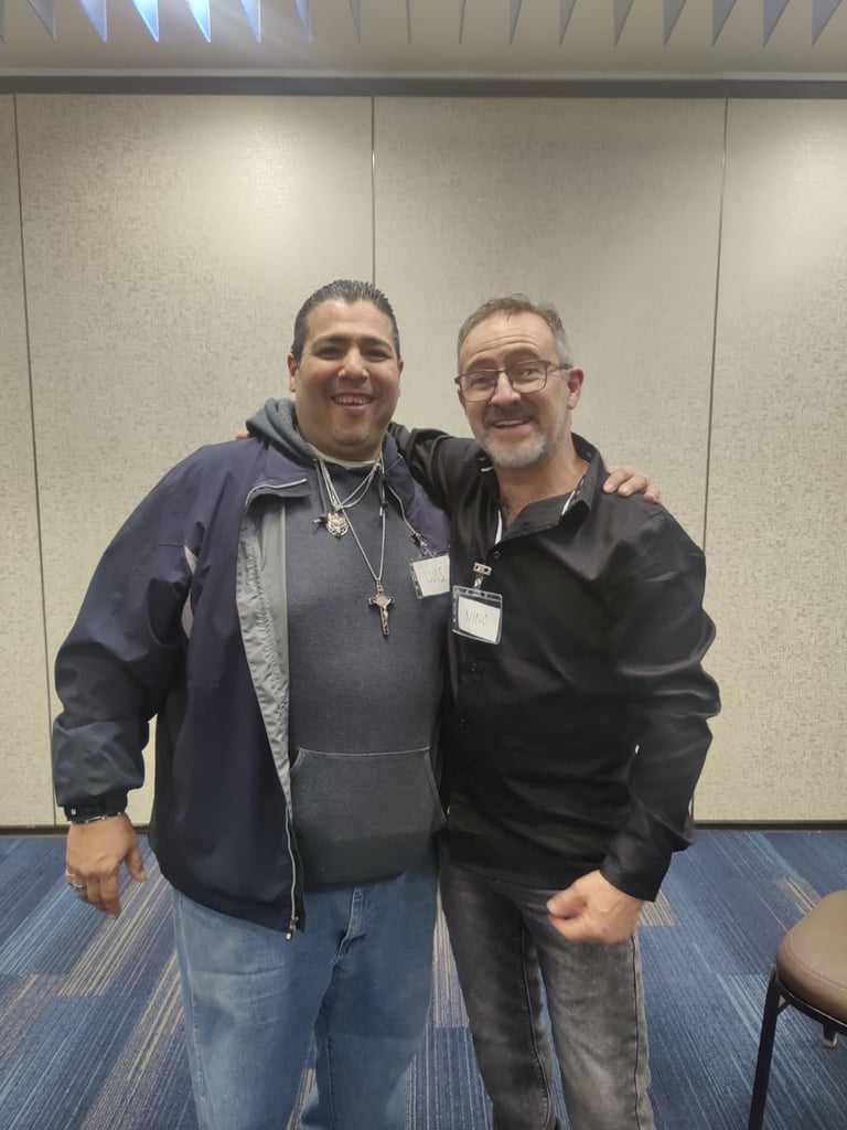 Two smiling men in casual attire posing together at a professional conference event.