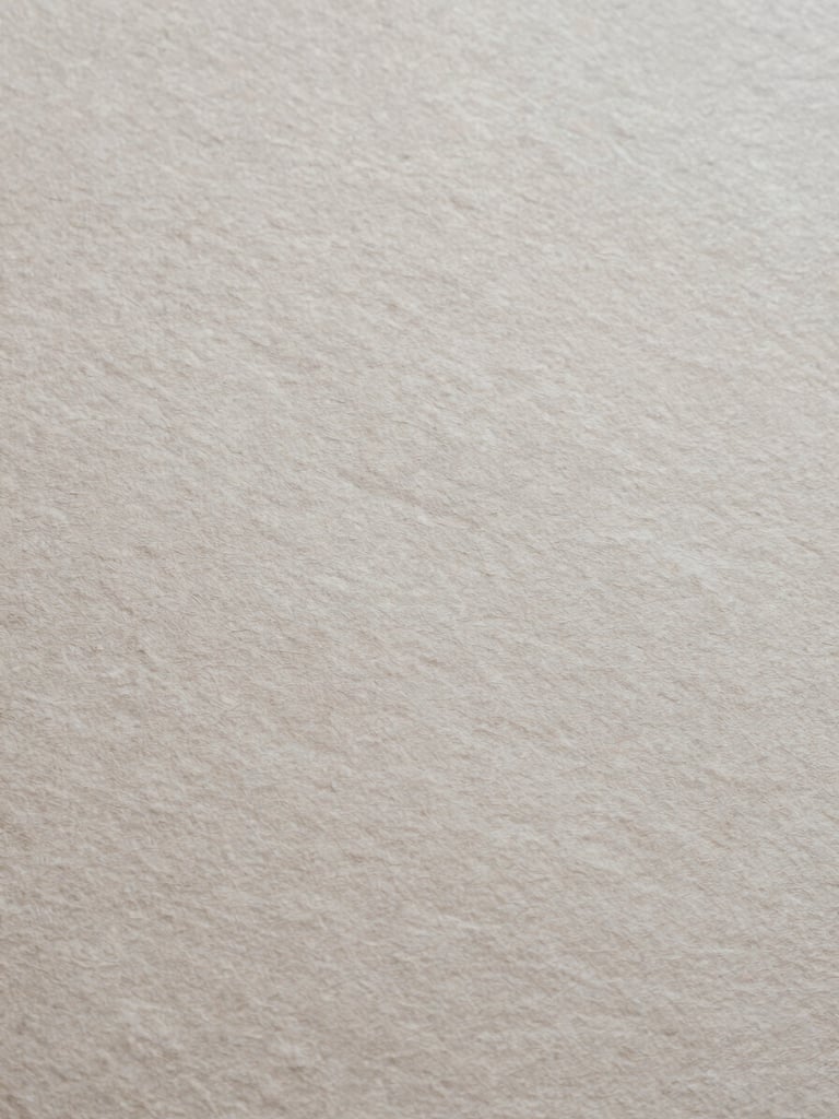 Extreme close-up of textured heavy handmade paper, soft natural overhead light, desaturated slate tones, 35mm film style.