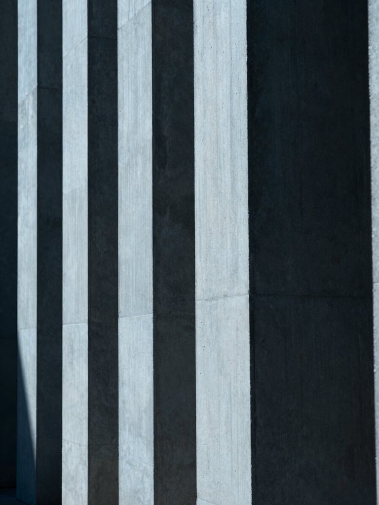 Tight abstract crop of clean concrete architectural columns, sharp geometric shadows, cool blue tone, 35mm lens.