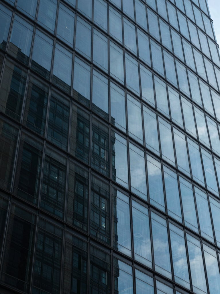 Macro low-key shot of a modern glass skyscraper facade in Madrid's financial district, cool blue tones, sharp geometric line work with deep shadows.