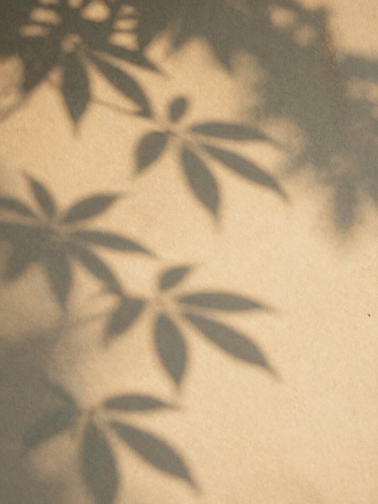 Soft shadow play of leaves on a warm sandy wall, diffused golden hour sunlight, organic textures, calm and reflective atmosphere, editorial photography.