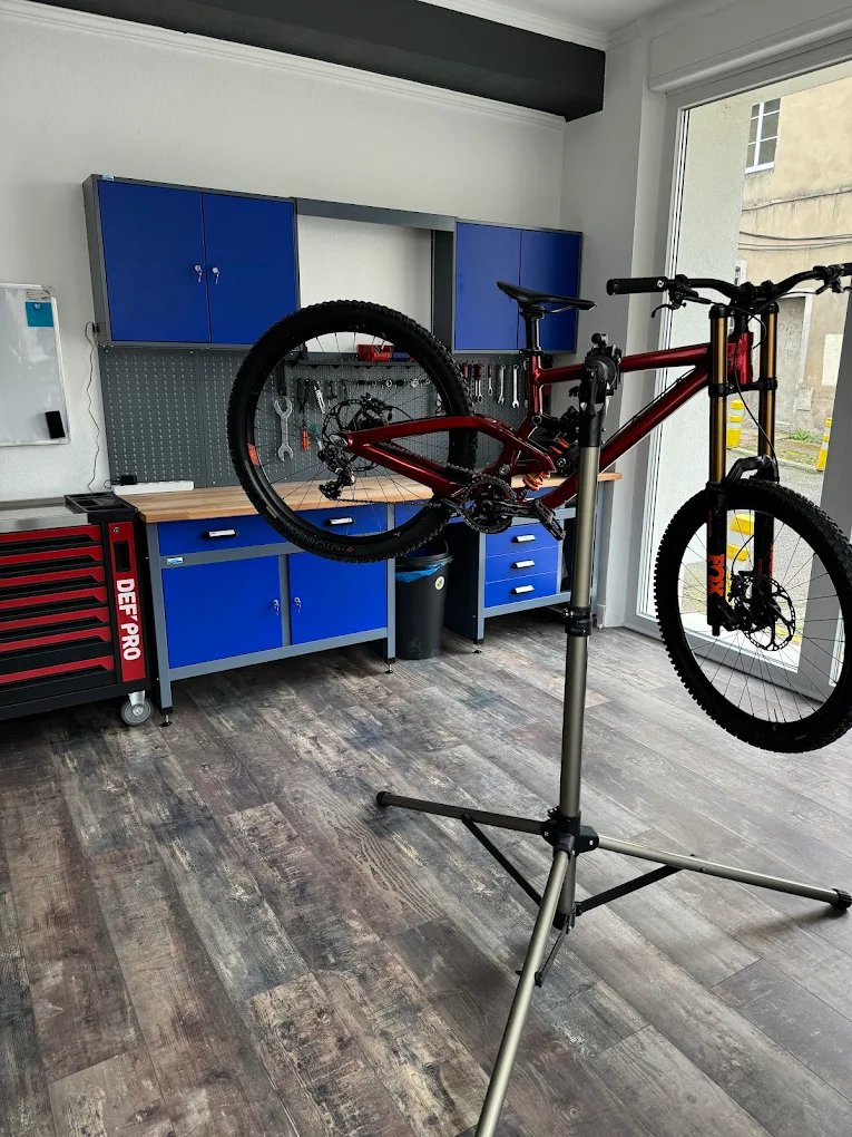 Red mountain bike on a professional repair stand in a modern bicycle workshop with blue tool cabinets.