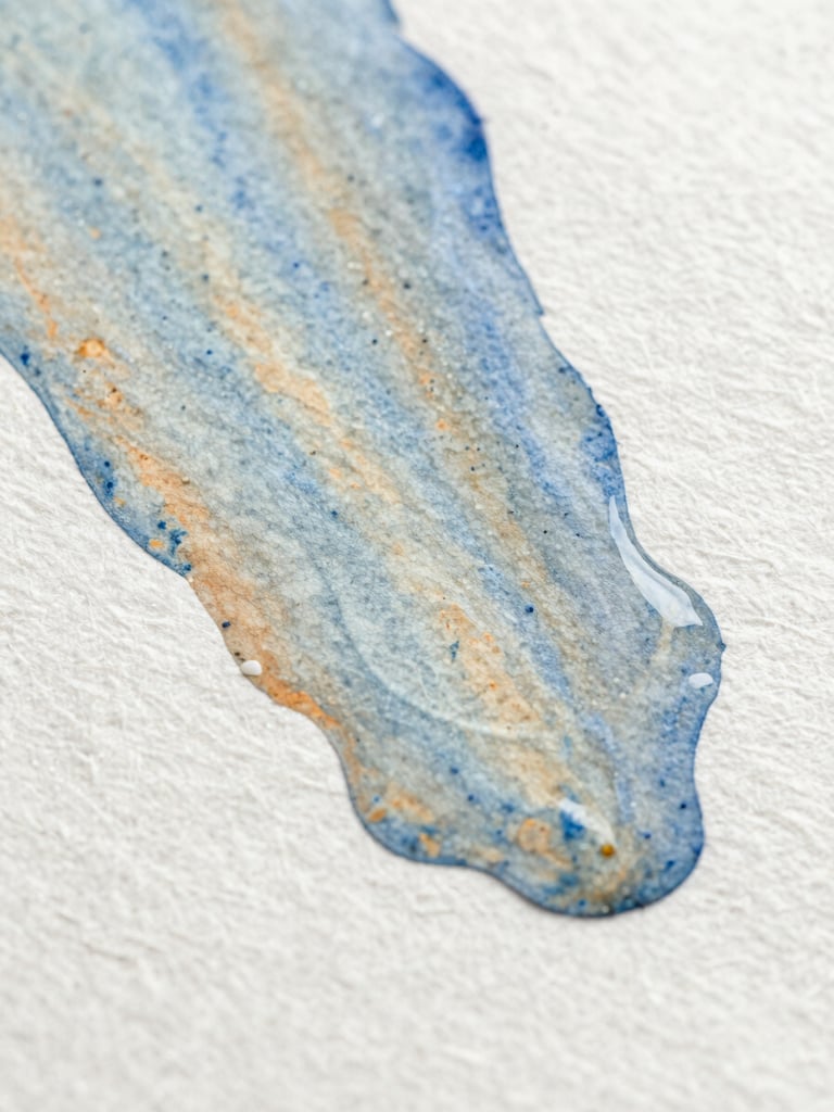 Macro close-up of wet watercolor pigment spreading on heavily textured cotton paper, soft blue and ochre tones, natural side lighting