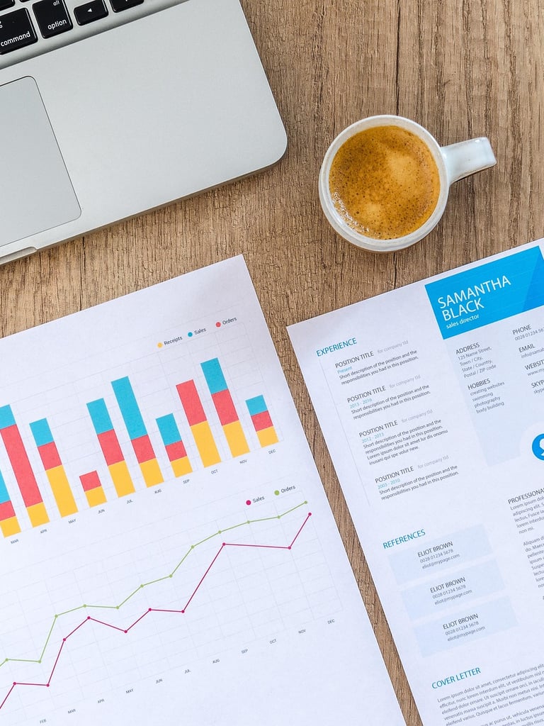laptop and printed charts on a wooden desk