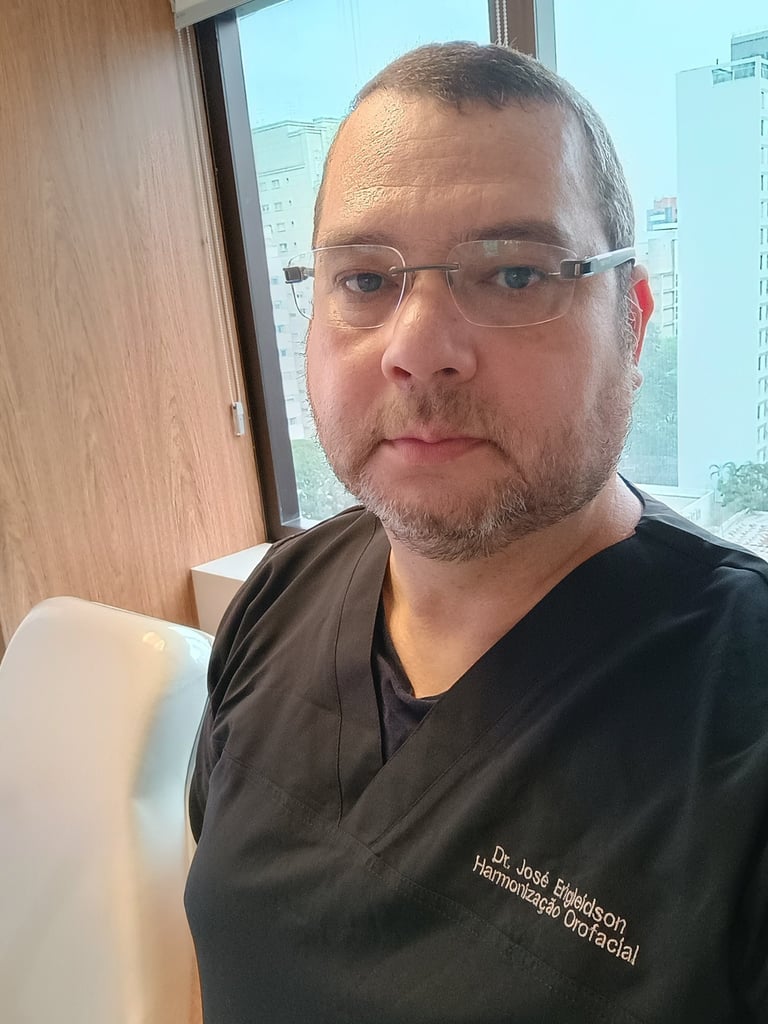 Dr. José Eri, especialista odontologia do sono, vestindo uniforme médico preto em um consultório.