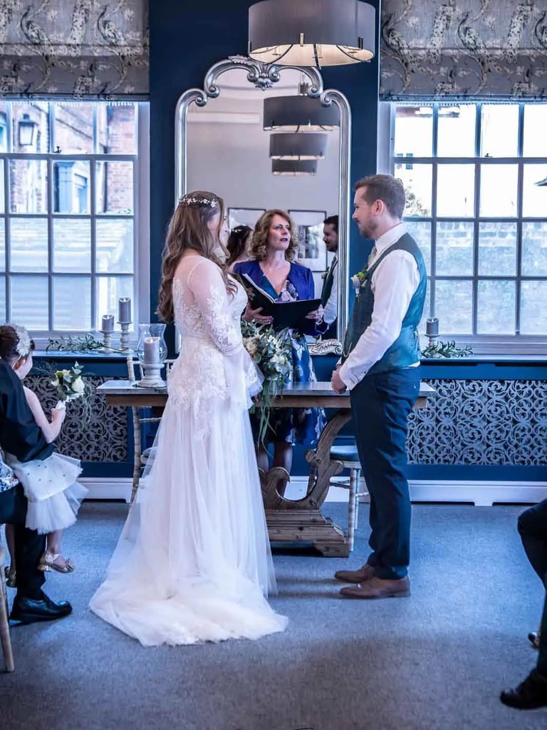 Bride and groom exchanging vows during an indoor wedding ceremony with a marriage celebrant.